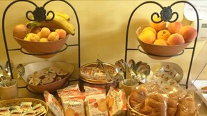 Un buffet proposant une variété d’aliments, notamment des fruits, du pain et des produits emballés.