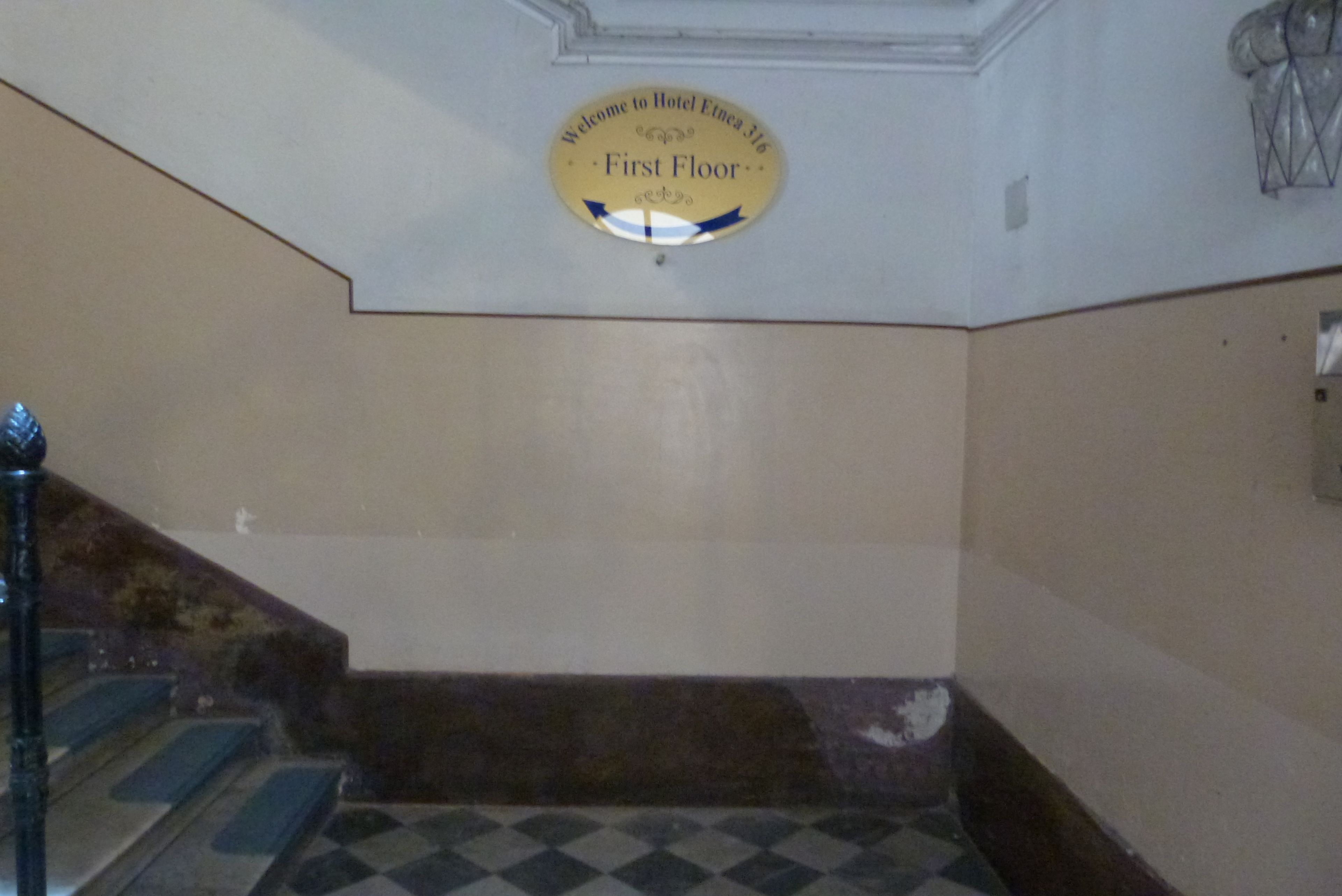 A first-floor sign in a building with a checkered floor pattern.