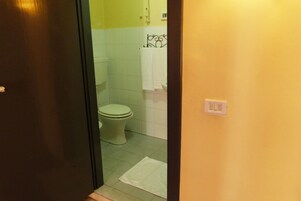 Un baño con inodoro, una toalla blanca y suelo de baldosas.
