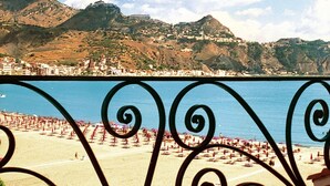 A coastal view with a beach, mountains, and a town in the background. - Sporting Baia Hotel (Giardini Naxos)