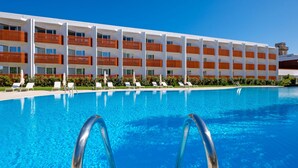Un hotel con piscina, varios balcones y tumbonas.