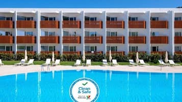 Relax by the pool with lounge chairs and umbrellas, surrounded by clean and safe facilities.
