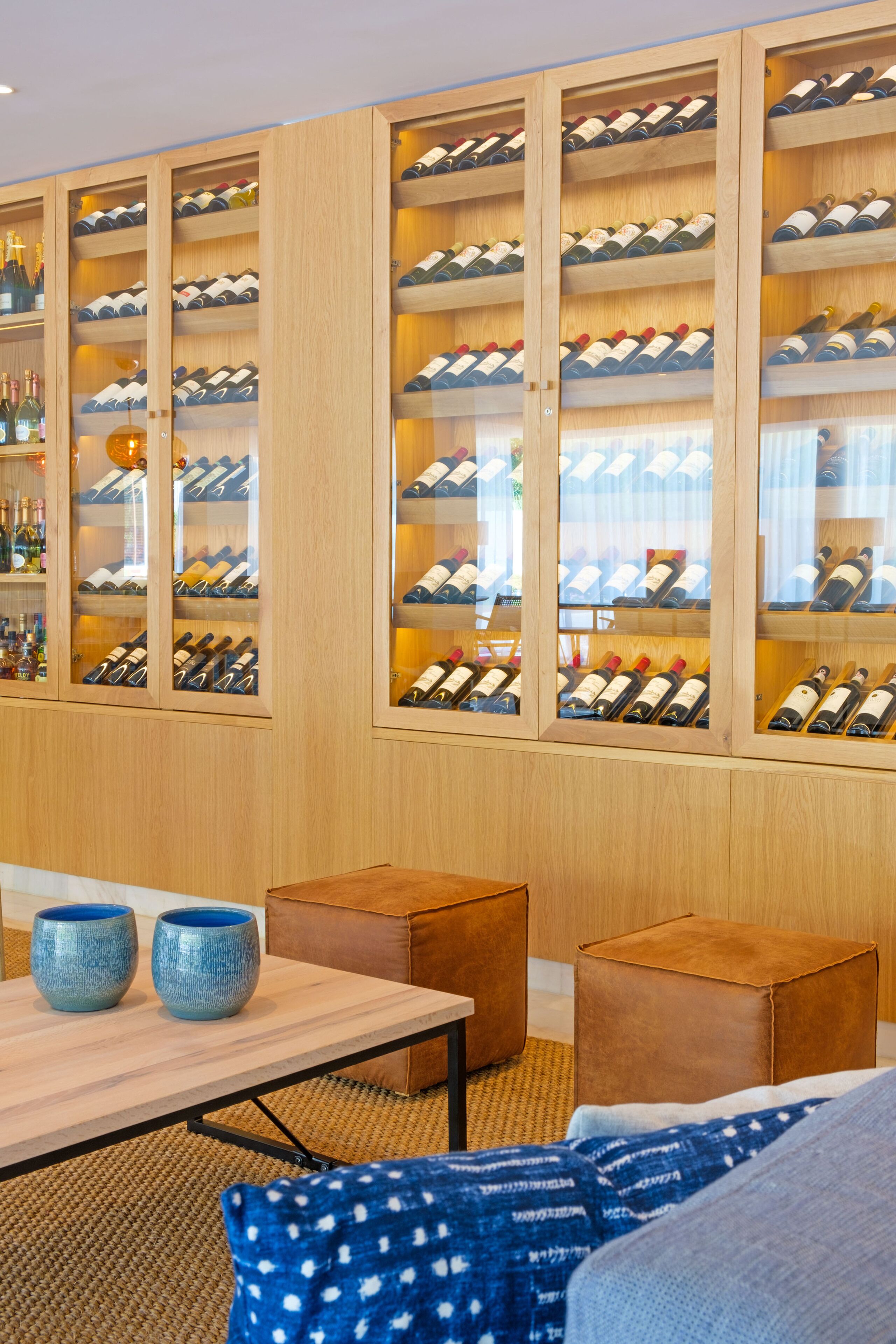 Une cave à vin avec des étagères en bois et une table sur laquelle sont posés des bols bleus.