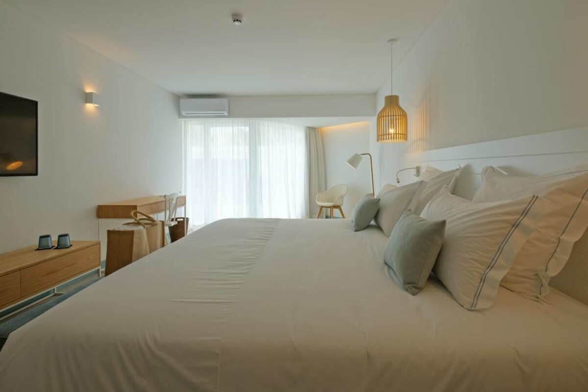 Een moderne hotelkamer met een groot bed, nachtkastjes, een bureau en een stoel.