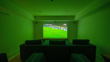 A room with a television displaying a sports event, a seating area with sofas, and a small table.