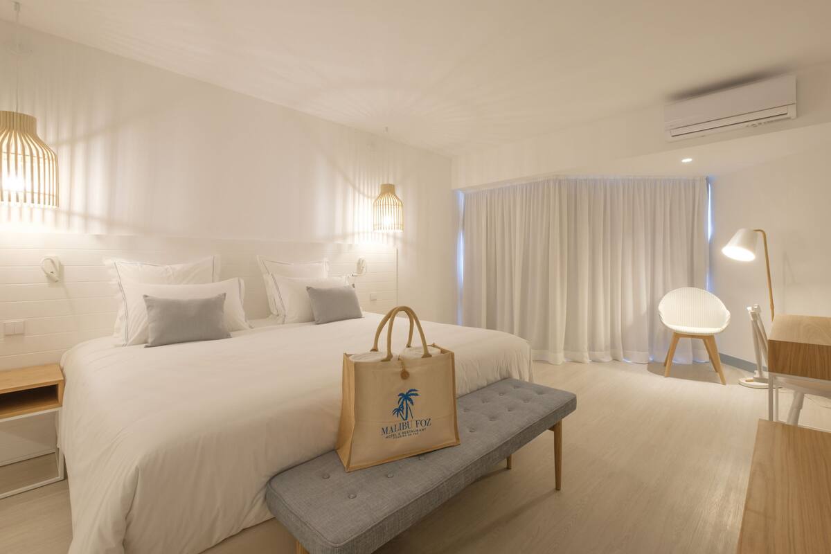 Ein Hotelzimmer mit einem großen Bett, einer Bank, einem Schreibtisch und einem Stuhl.