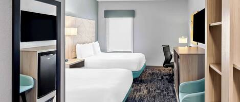 A hotel room with two beds, a desk, a chair, a TV, a lamp, and a wardrobe.
