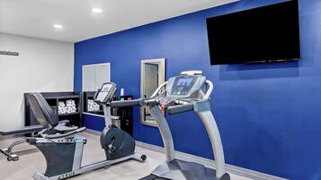 A gym with a treadmill, elliptical, and weight machine.