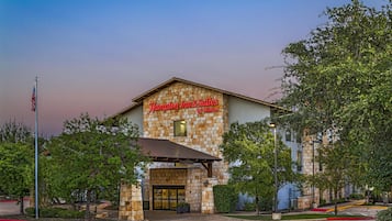 Um hotel com fachada de pedra e uma placa com a inscrição 'Hampton Inn & Suites by Hilton'.