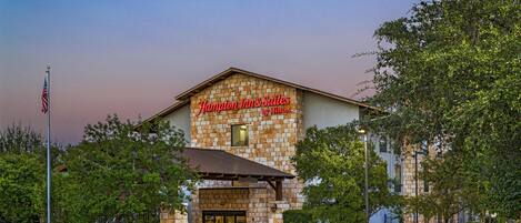 A hotel with a stone facade and a sign that reads 'Hampton Inn & Suites by Hilton.'