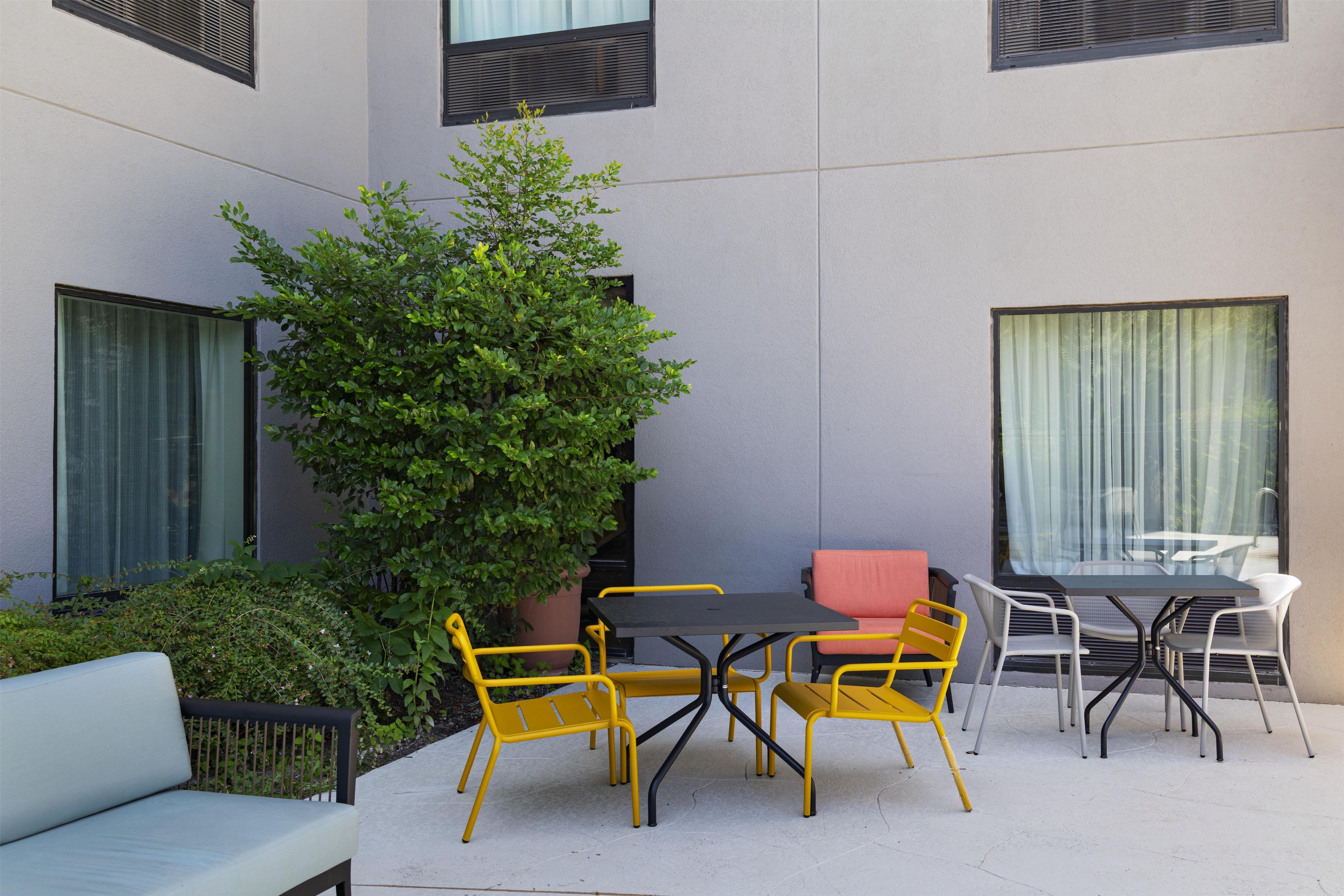 An outdoor seating area with a table and chairs, a potted plant, and a sofa.