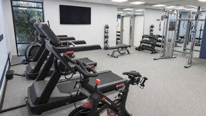 Une salle de sport équipée de tapis de course, de vélos elliptiques et de matériel de musculation.