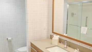 Un baño moderno con un espejo grande, dos lavamanos, un inodoro y una ducha.
