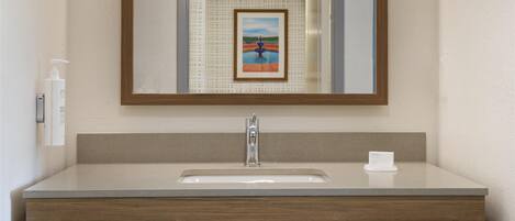 Un baño moderno con un espejo grande, un lavamanos y un perchero para toallas.