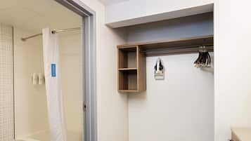 Een badkamer met een bad, douche, handdoekhouder en een plank met toiletartikelen.