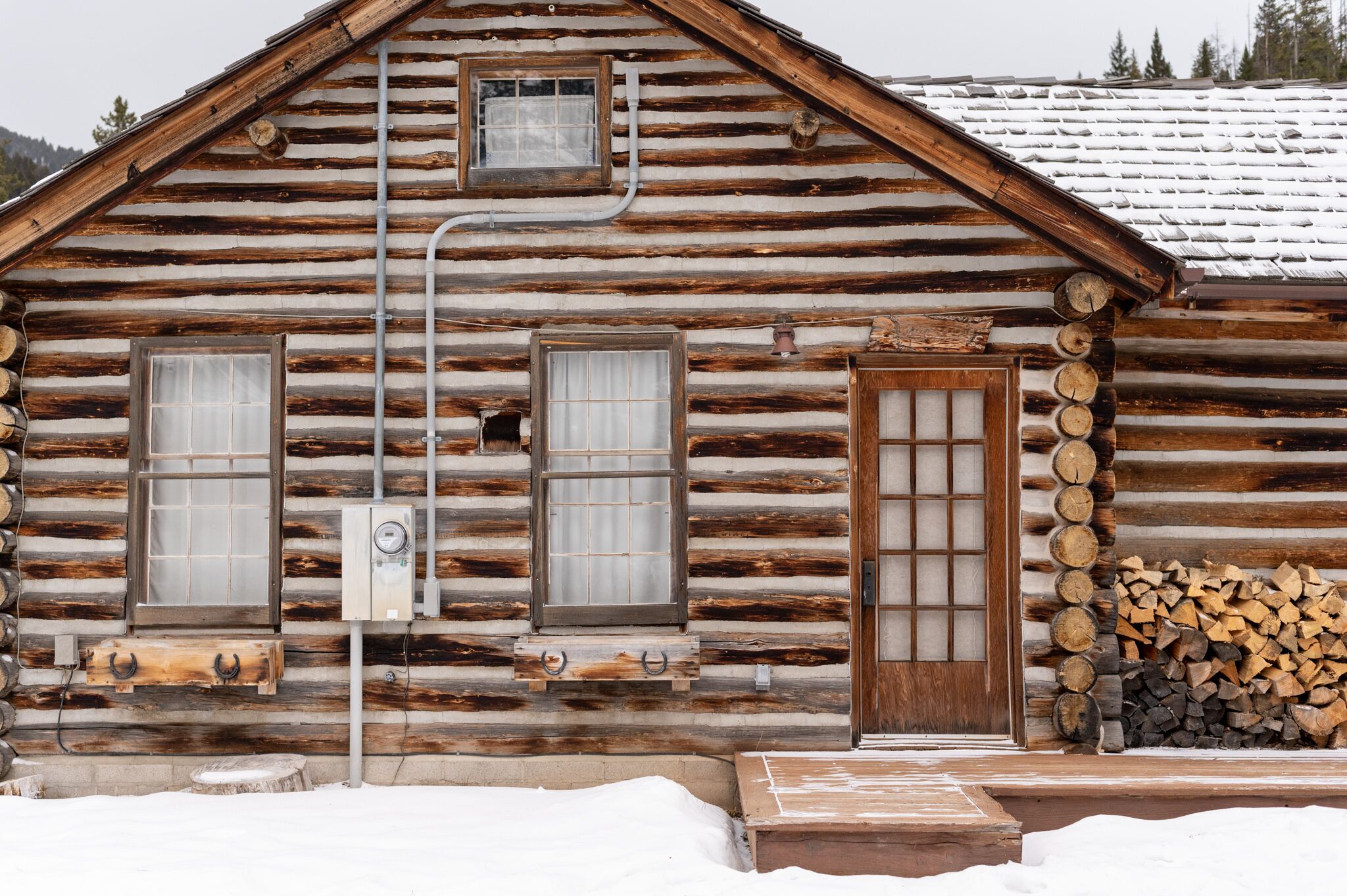 A log cabin with two windows, a door, and a small porch area.