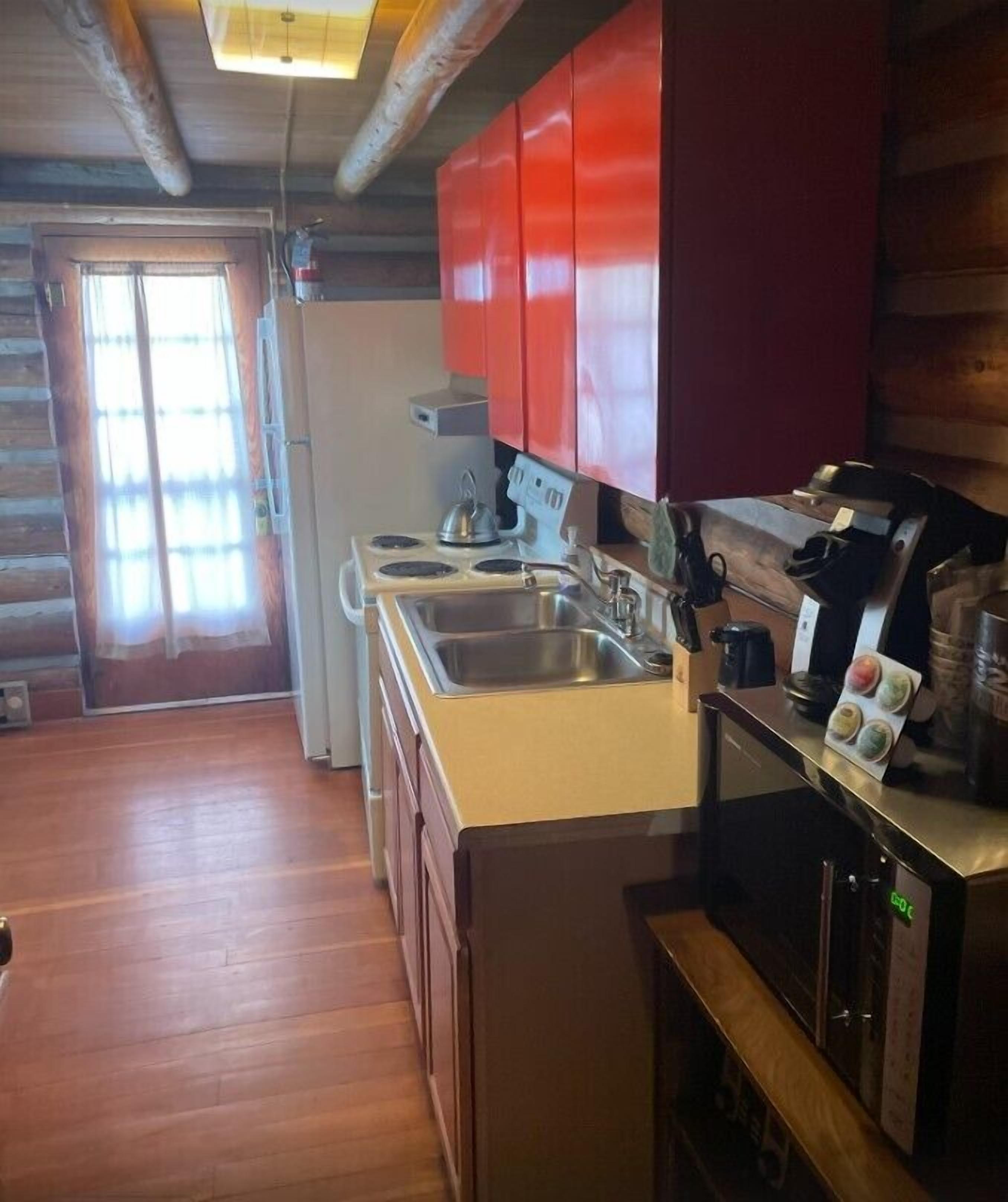 A compact kitchen with wooden cabinets, a stove, and a sink.