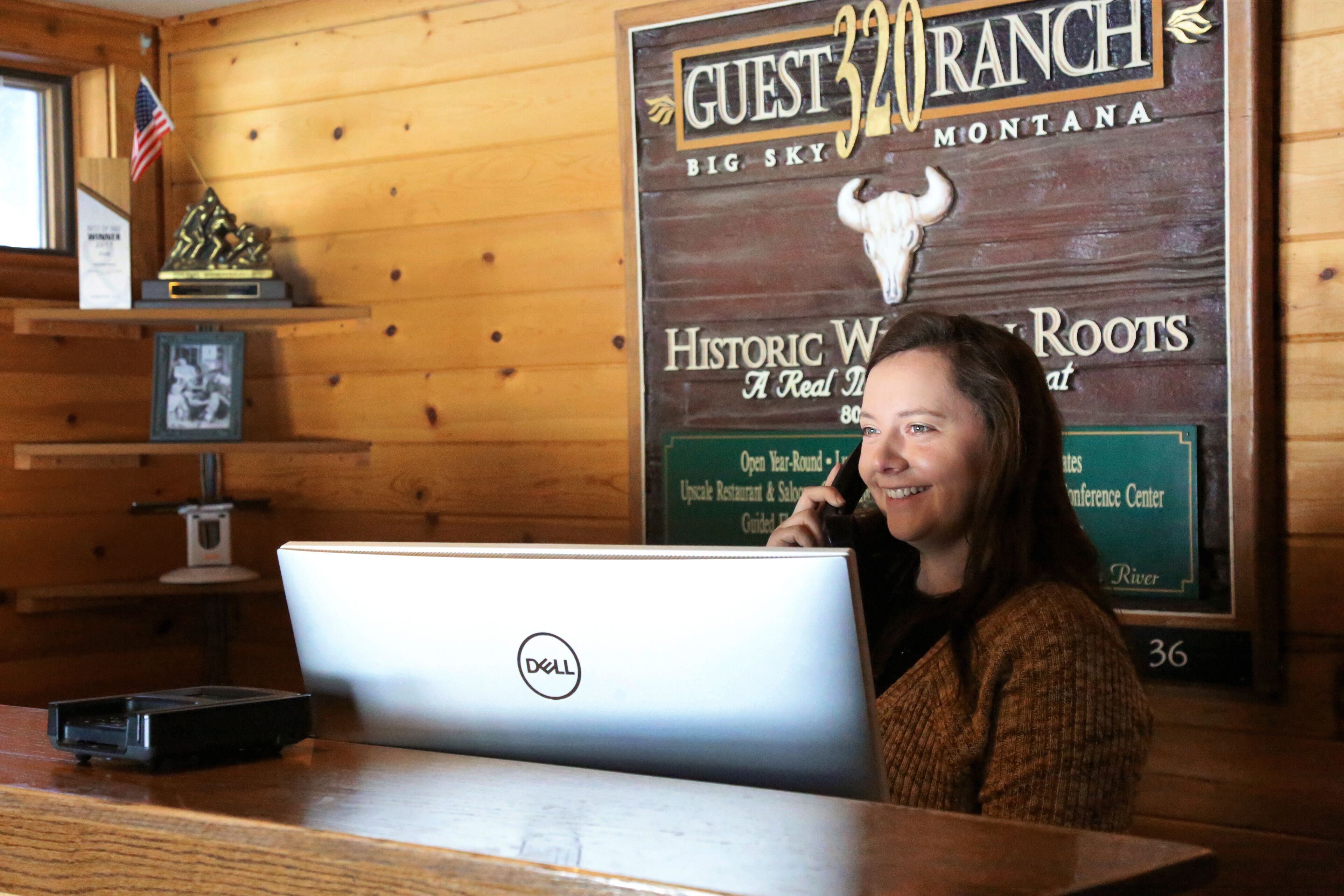 Un intérieur en bois avec un bureau, un ordinateur portable et une pancarte indiquant « RANCH POUR LES VISITEURS ».