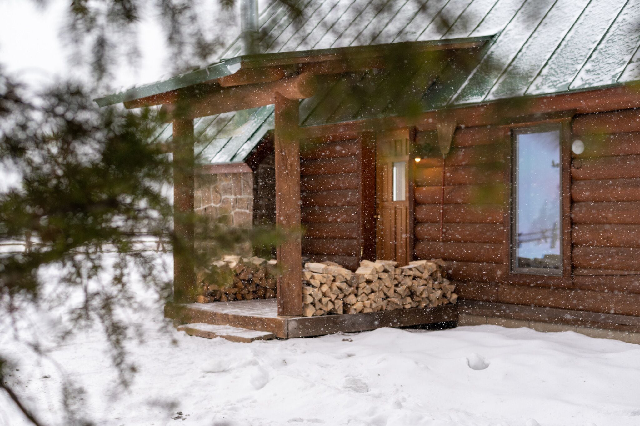A wooden cabin with a covered porch and a stone foundation.