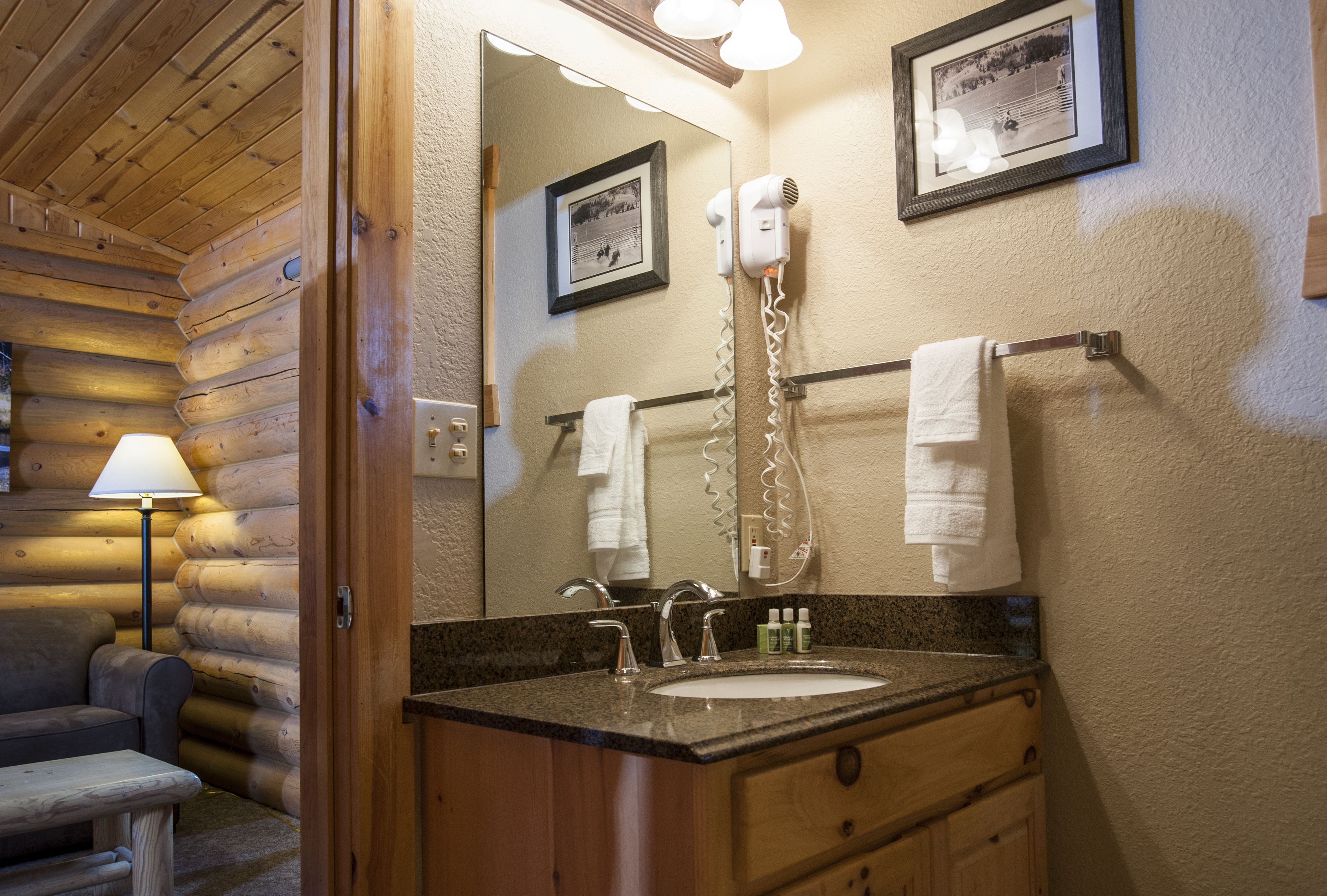 A log cabin bathroom with a sink, mirror, towel rack, and a hairdryer.