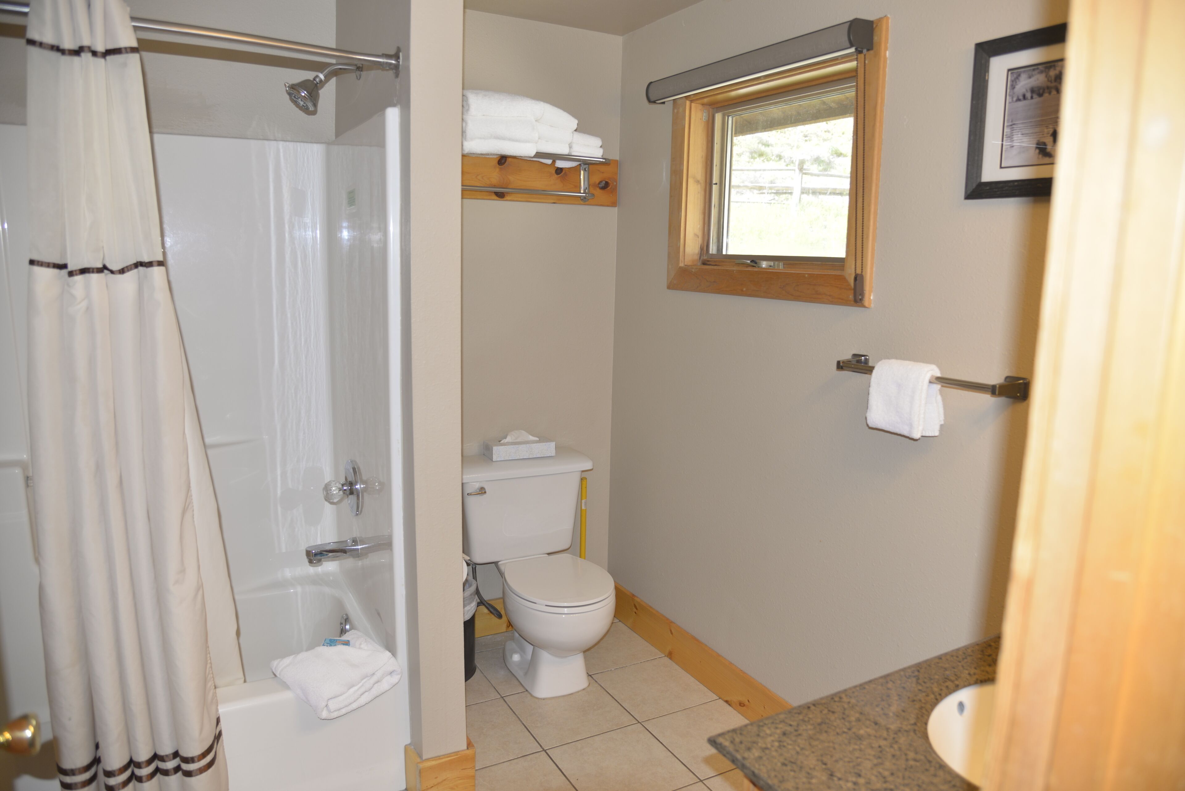 A bathroom with a bathtub, toilet, and a window.