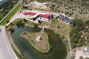 An aerial view of a property with a large building, a parking lot, and a pond.