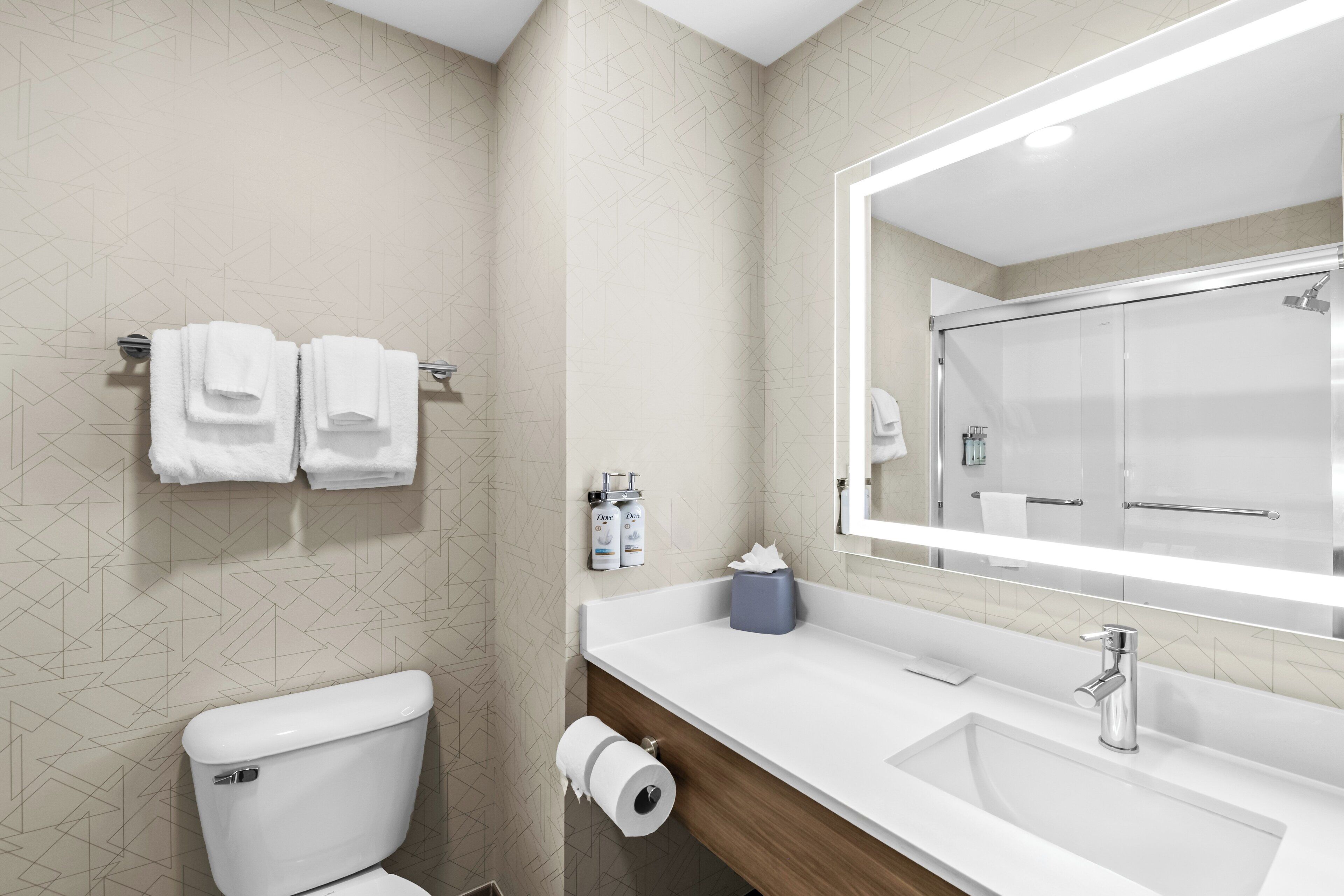 A modern bathroom with a toilet, a sink, and a large mirror.