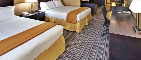 A hotel room with two beds, a desk, a television, and a kitchenette.