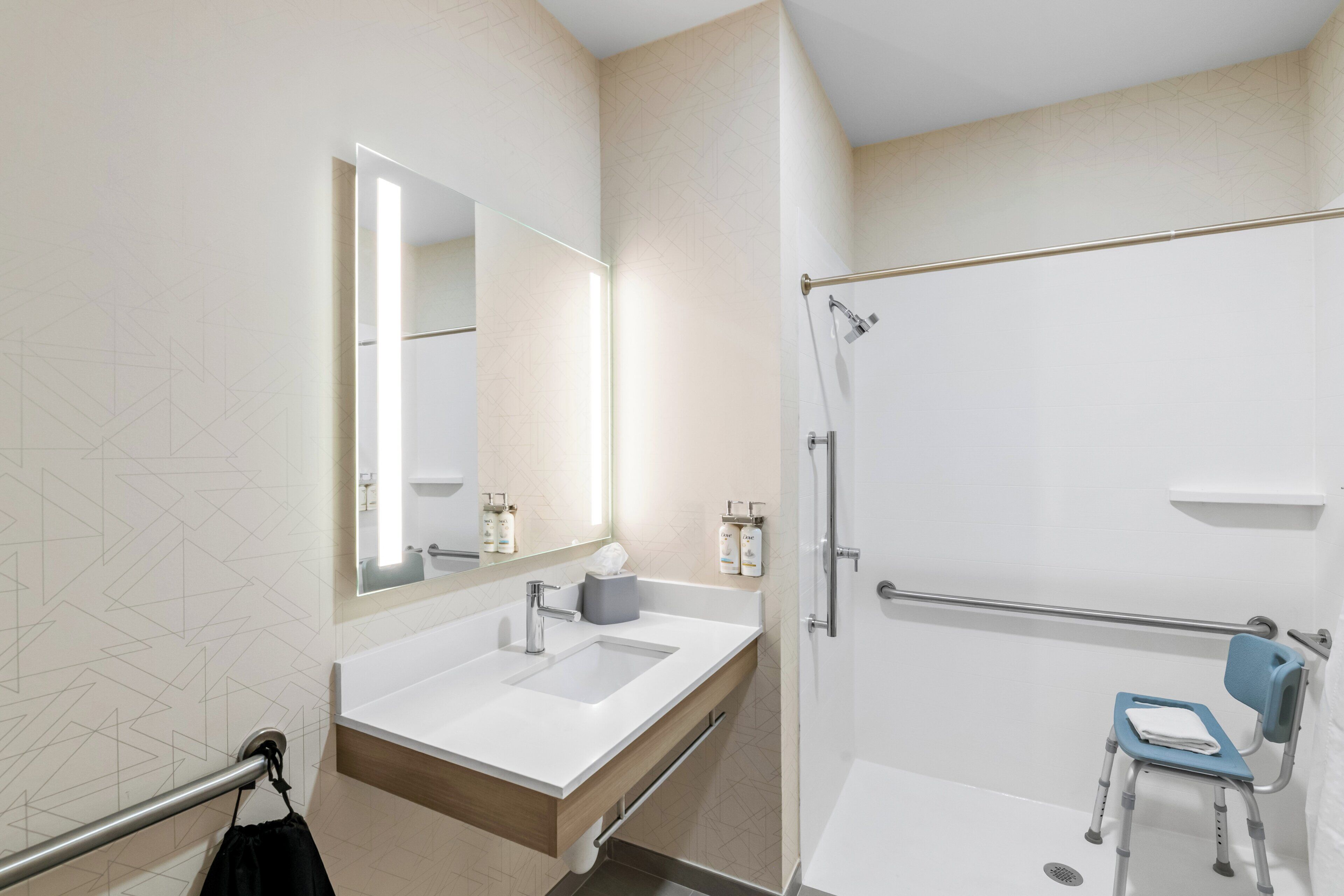 A modern bathroom with a large mirror, a sink, and a shower area.