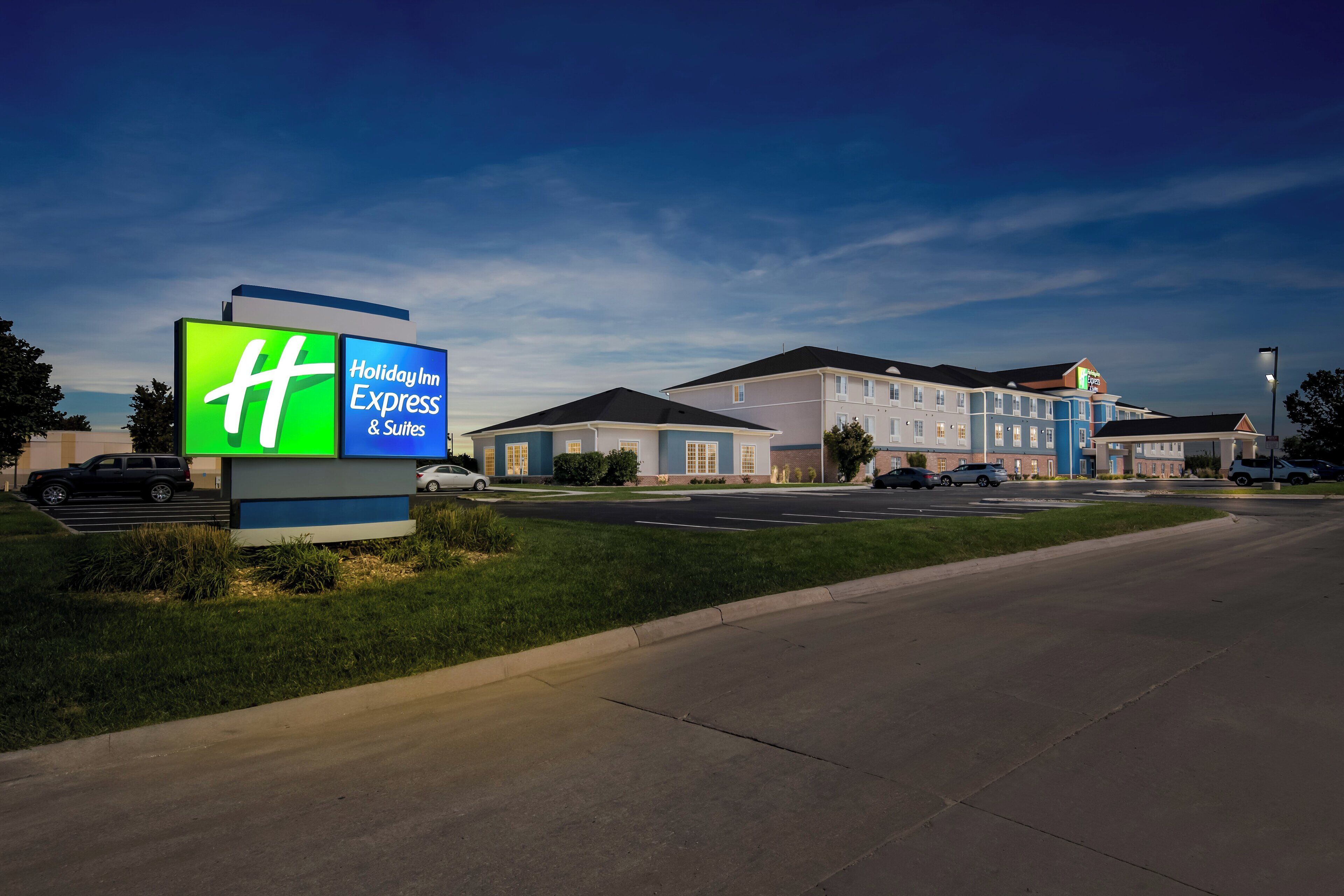 Un hôtel Holiday Inn Express & Suites, reconnaissable à son grand panneau, composé de plusieurs bâtiments et doté d’un parking.