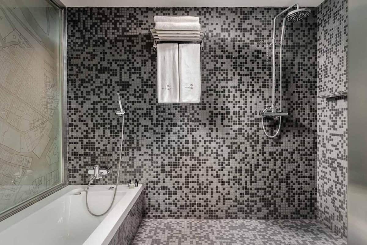 Un baño con ducha de mosaico, bañera y ventana con un mapa.