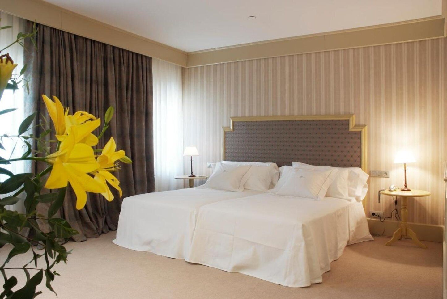 Una habitación de hotel con una cama grande, dos mesitas de noche y un cabecero.