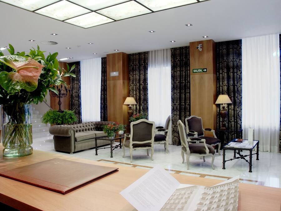 Vestíbulo de hotel con mostrador de recepción, zona de estar y un letrero que indica la salida.