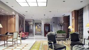 Un vestíbulo amplio con suelo a cuadros, una escalera monumental y muebles elegantes.