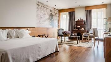 A hotel room with a large bed, a desk, a chair, a bookshelf, and a large window with curtains.