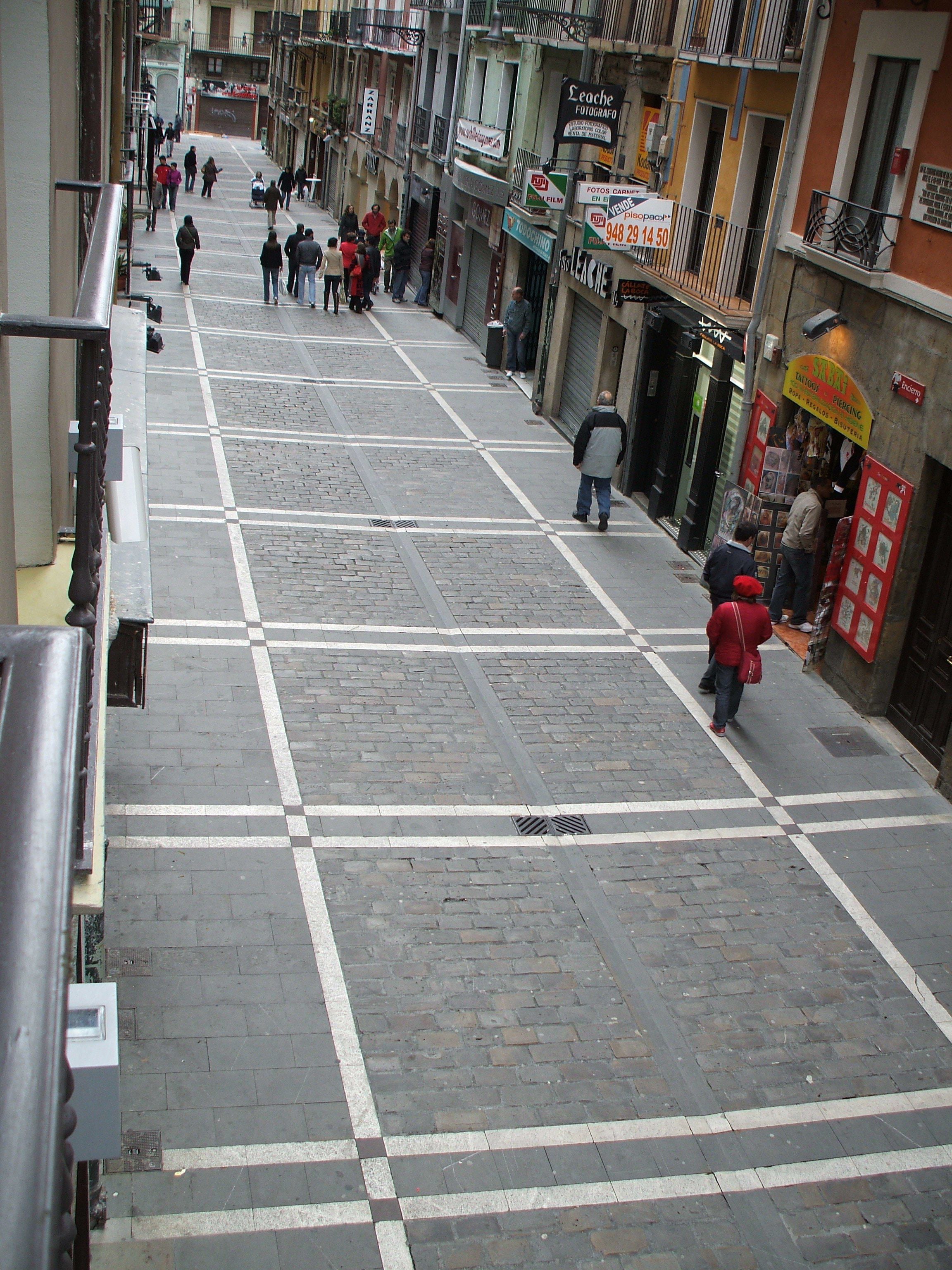 Una calle peatonal con tiendas y un edificio cerrado con persianas.