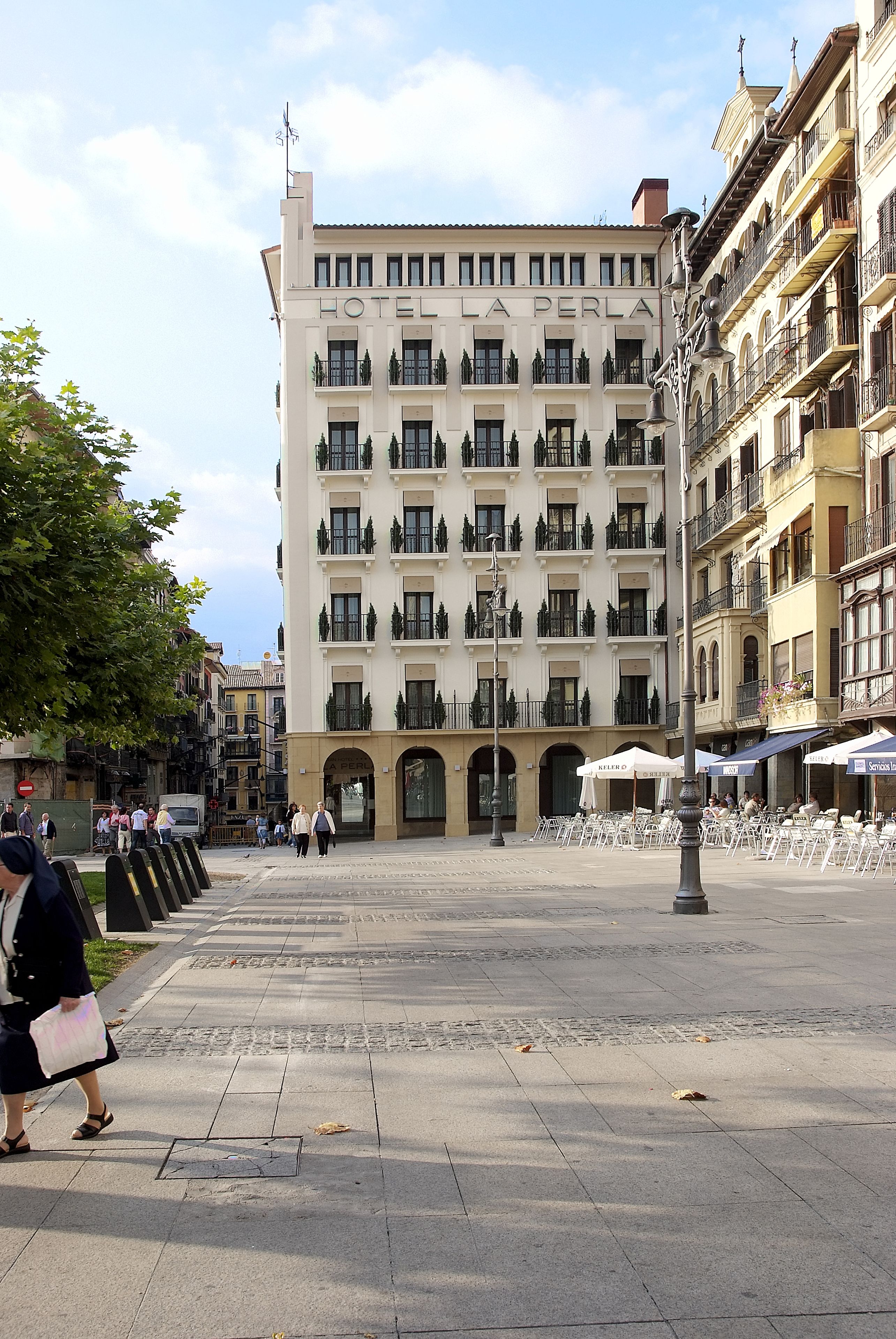 A hotel named "HOTEL LA PERLA" with a classic architectural style, featuring multiple balconies and a central entrance.