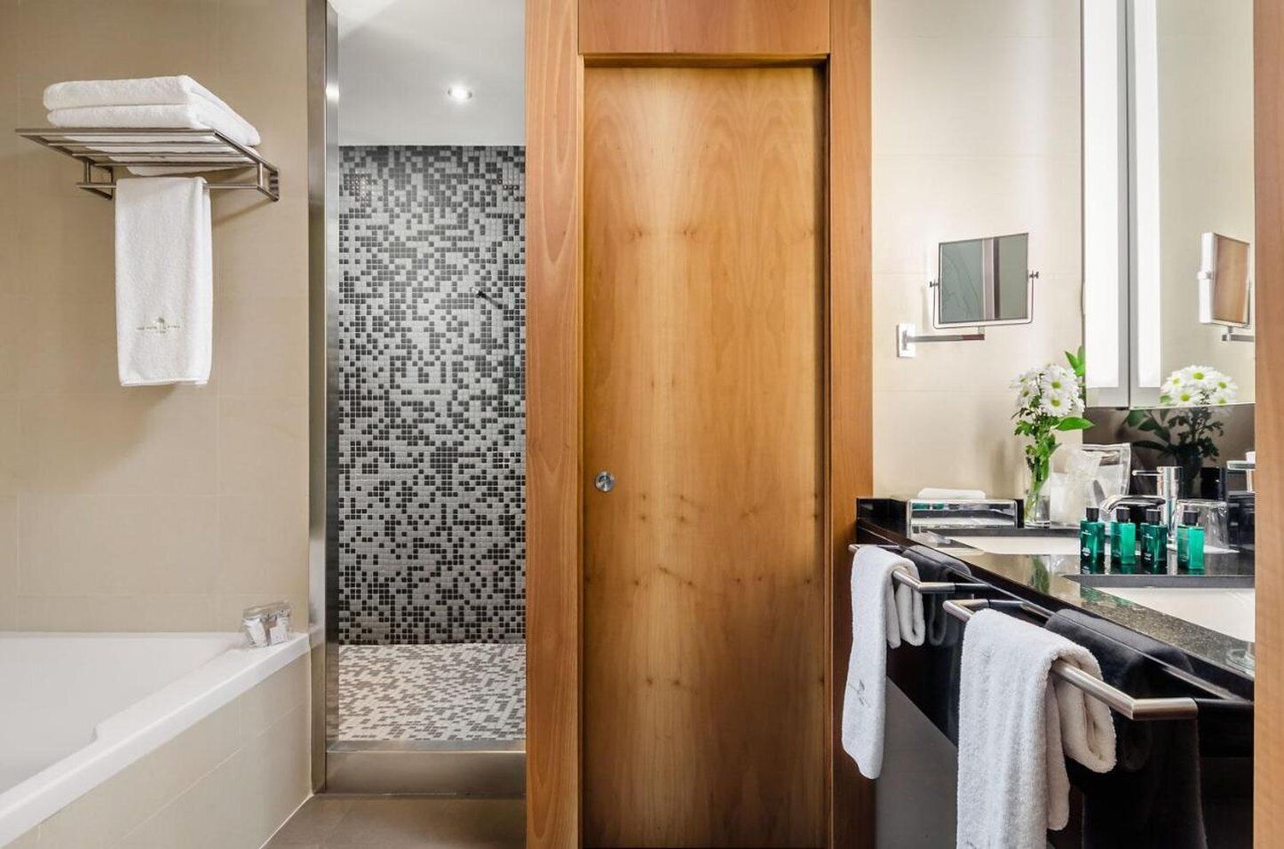 Un baño moderno con ducha, una puerta de madera, un tocador con espejo y un perchero para toallas.