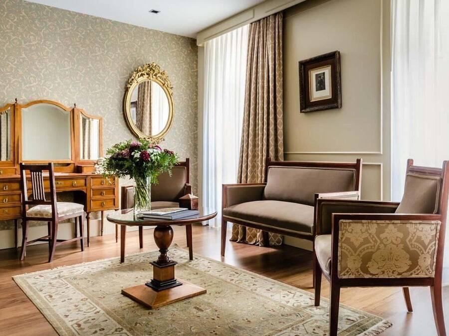 A well-appointed living room with a wooden desk, a comfortable sofa, a round coffee table, and a large mirror.
