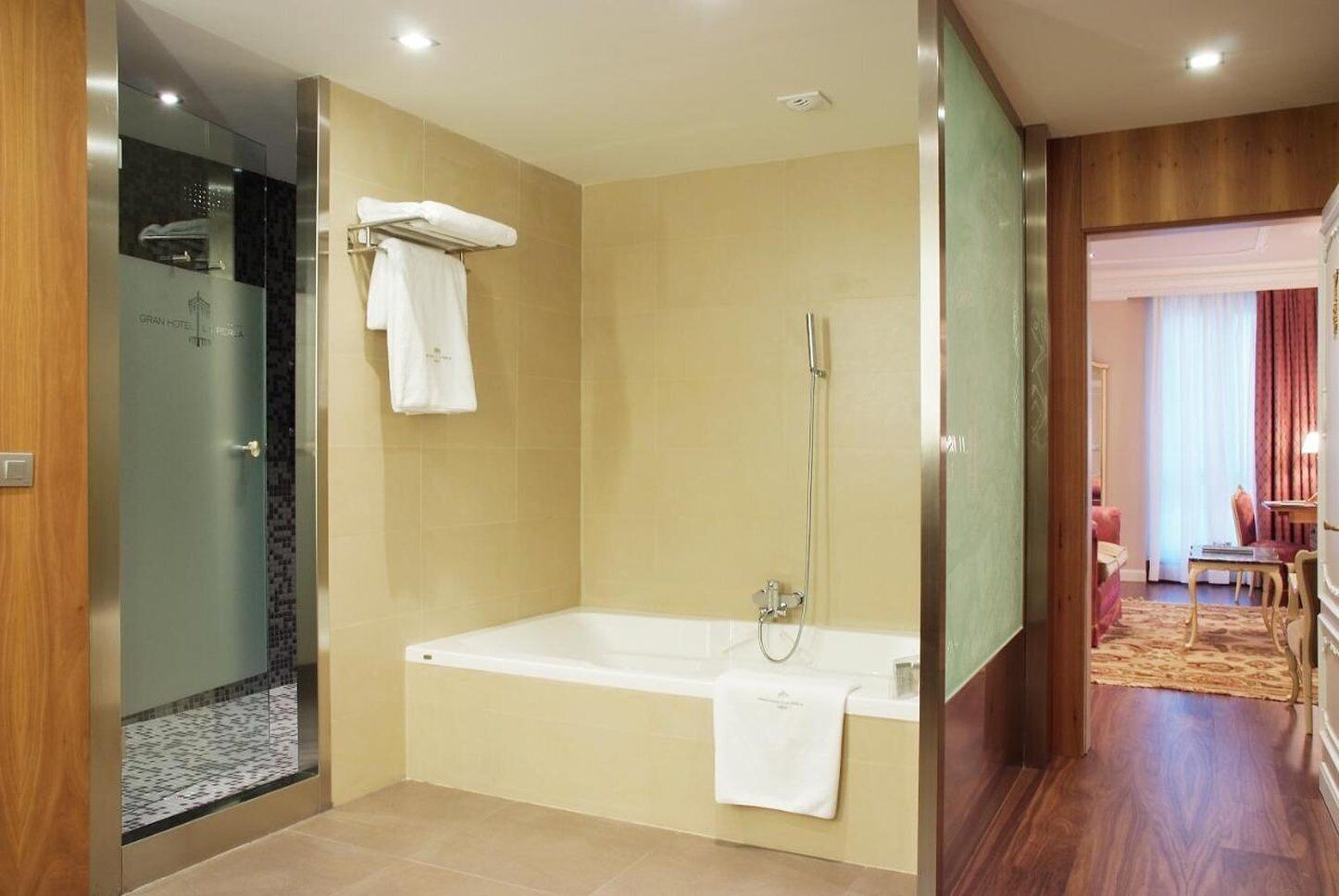 Un baño moderno con bañera, ducha y zona de ducha con mampara de vidrio.