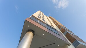 A modern building with a prominent central column, large windows, and a clear sky.