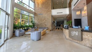 A spacious lobby with a reception desk, seating area, and large windows offering views of the outdoors.