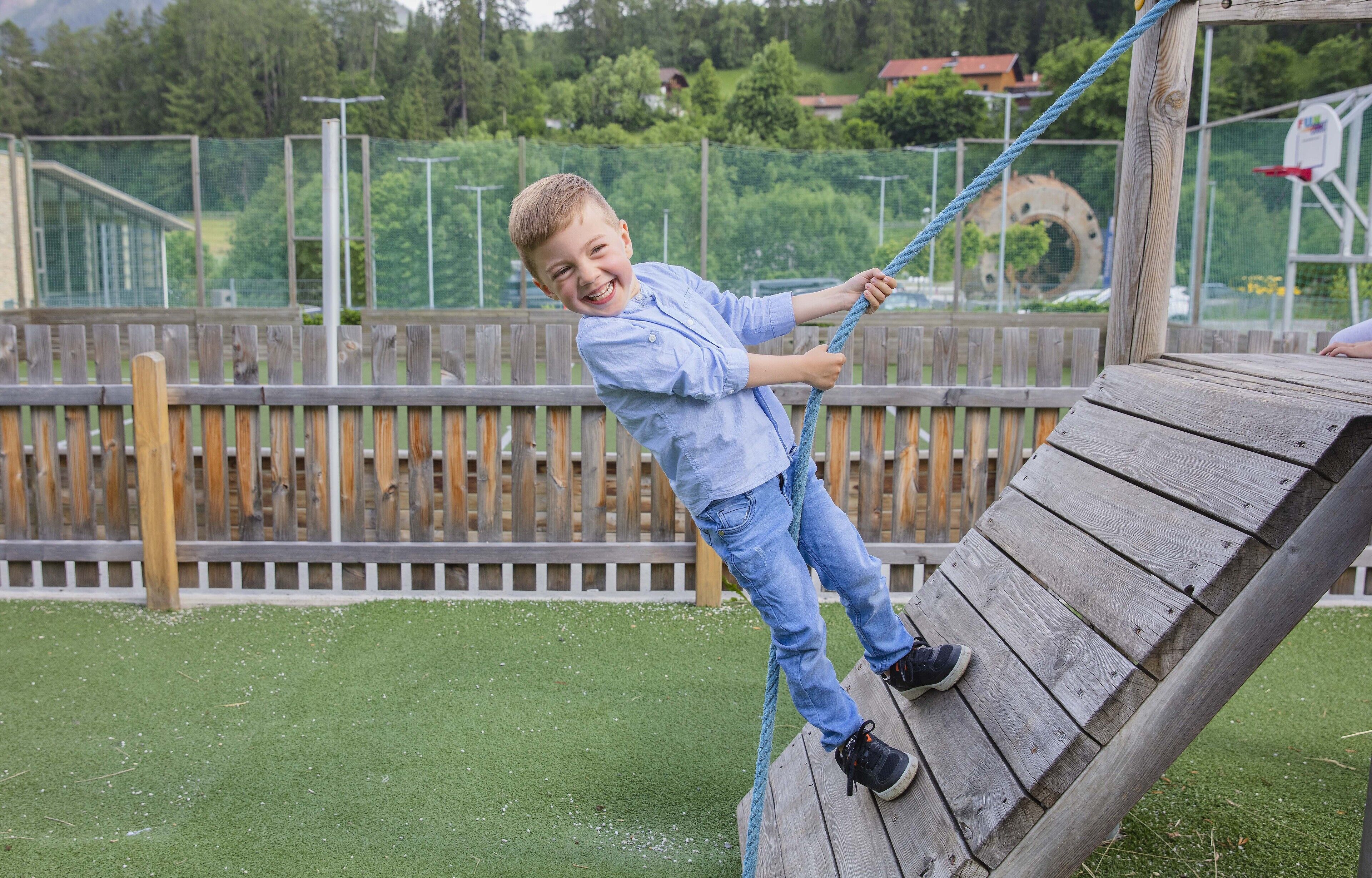 Un enfant qui grimpe sur une structure en bois dans un parc.