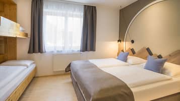 Ein Hotelzimmer mit einem hölzernen Bett, einem Vorhangfenster, einem Heizkörper und einer Lampe.