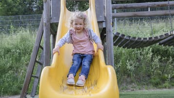 Children can play safely in the outdoor play area with a fun slide and lush surroundings.