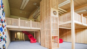 A multi-level wooden play area with a slide and climbing wall. - JUFA Hotel Wipptal (Steinach am Brenner)