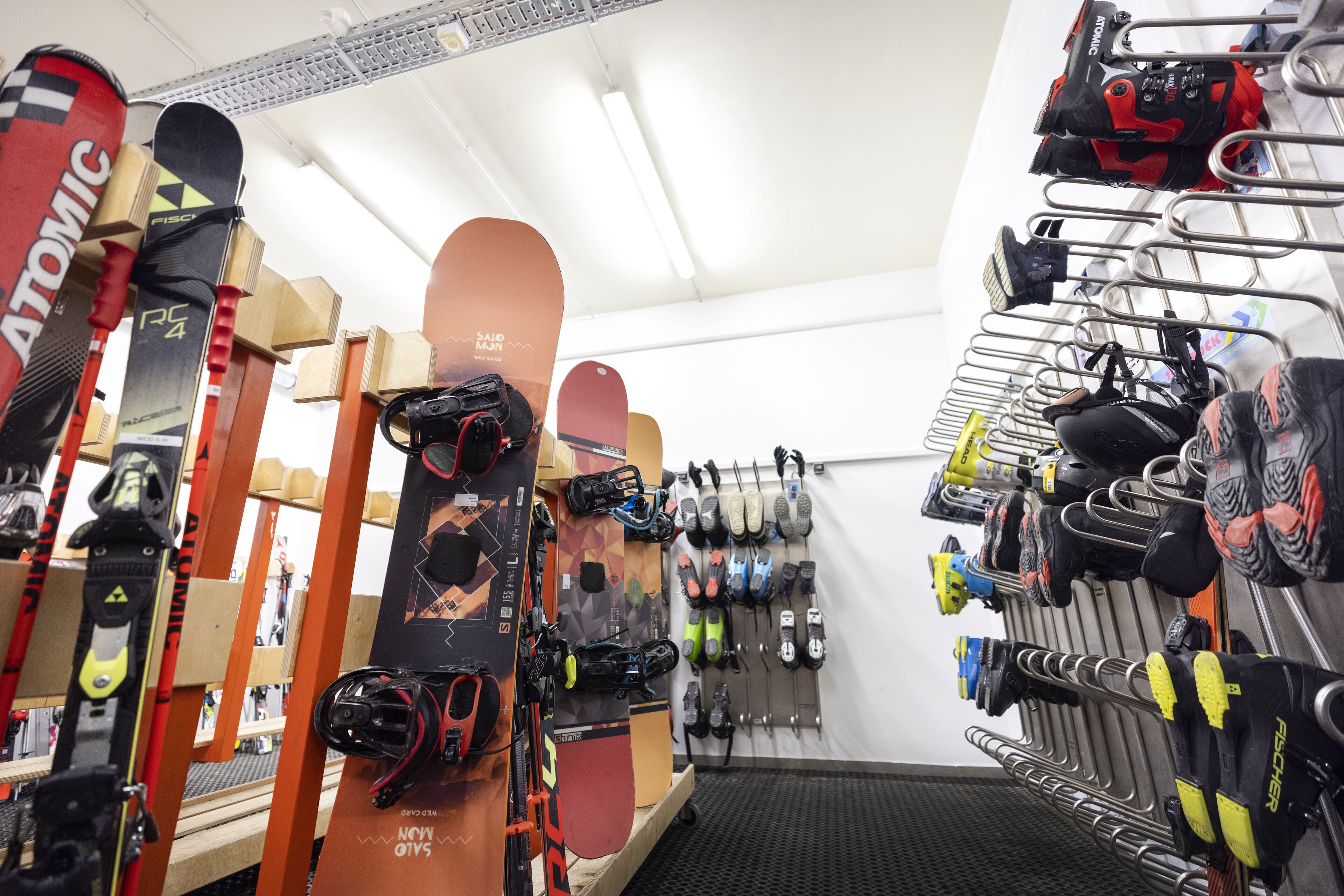 A ski equipment store with various skis, snowboards, and boots displayed on shelves and racks.