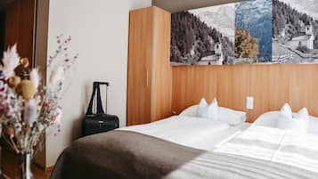 Una habitación de hotel con una cama grande, un armario de madera y un cuadro de un paisaje montañoso.