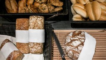 Variedad de panes y pasteles expuestos en cestas y sobre una superficie de madera.