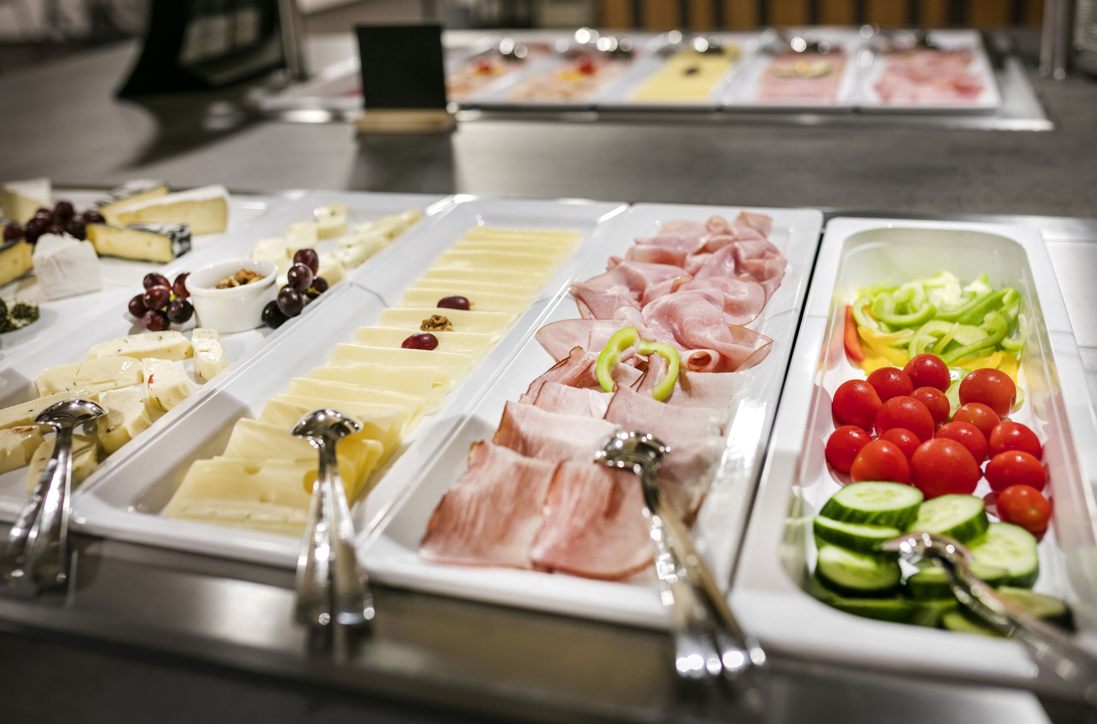 Un buffet con diversi cibi, tra cui formaggi, salumi e verdure.